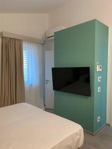 1 dormitorio con 1 cama y TV en la pared en Naturamare B&B, en Villapiana