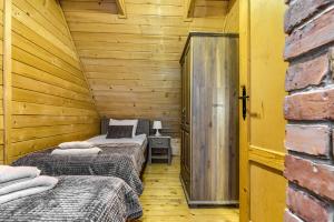 two beds in a room with wooden walls at Oaza Mazurska - Domek z kominkiem in Piecki +44 photos