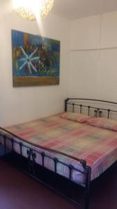 a bed in a room with a painting on the wall at Cocoa Mews Cafe and Homestay in George Town