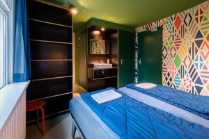 a small room with a bed with a blue sheet at Stayokay Hostel Dordrecht - Nationaal Park De Biesbosch in Dordrecht +41 photos