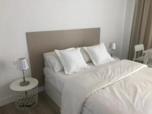 a bedroom with a white bed with white sheets and pillows at Carihuela Beach Apartamentos in Torremolinos