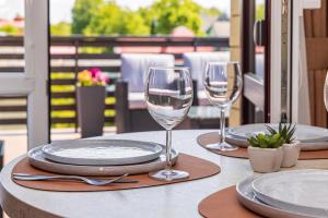 a table with plates and wine glasses on a balcony at Palangos Vila Apartments in Palanga