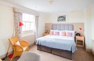 a bedroom with a large bed with pink pillows at Crown Hotel in Southwold