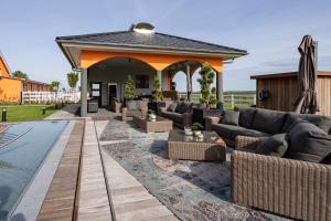 eine Terrasse mit Sofas und einem Pool in der Unterkunft Luxus Resort Rügen Residenz Kubitzer Bodden in Rambin