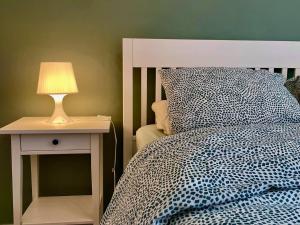 um quarto com uma cama e um candeeiro numa mesa de cabeceira em L'appartement d'houyet - Esc'Appart em Houyet