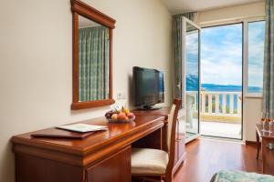 a room with a desk with a television and a balcony at Hotel Villa Bacchus in Baška Voda