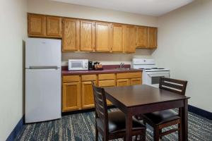 a kitchen with a table and a white refrigerator at AmericInn by Wyndham Wausau in Weston