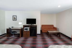 a hotel room with a television and a desk and a chair at Ramada by Wyndham Maggie Valley in Maggie Valley