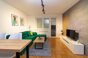 een woonkamer met een groene bank en een tafel bij M&A apartment in Lukavica