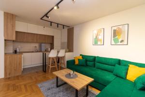 a living room with a green couch and a kitchen at M&A apartment in Lukavica