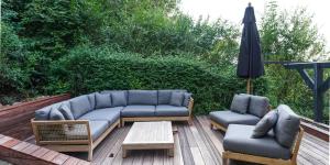 um pátio com um sofá, 2 cadeiras e um guarda-sol em Les Terrasses des Falizes B&B em Rochefort