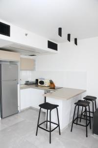 a kitchen with white cabinets and a counter with stools at Apartments4you Leonardo 17 in Bat Yam