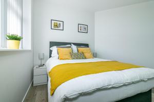 a white bedroom with a large bed with yellow pillows at Executive Apartment Close to Station in Hatfield