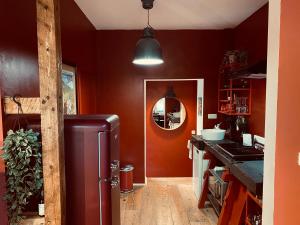 una cucina con pareti rosse e frigorifero metallico di La Duchesse d'Aumale a Spa