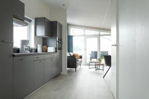 uma cozinha com armários cinzentos e uma sala de estar em Chalet bis sechs Personen ohne Hund - a61186 em Norden