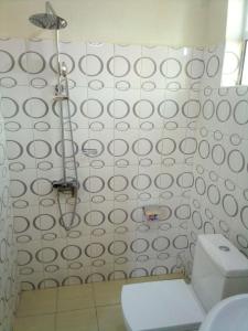 a bathroom with a white toilet and a shower at Dich Comfort Hotel University Branch in Gulu