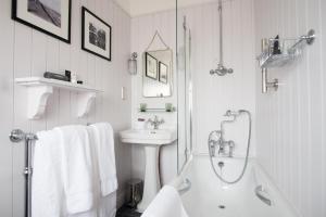 a white bathroom with a tub and a sink at The Swan Hotel in Southwold