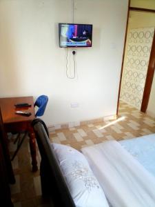 a room with a bed and a tv on the wall at Dich Comfort Hotel University Branch in Gulu