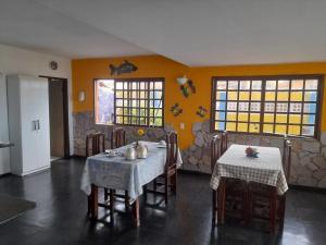 a dining room with two tables and chairs and yellow walls at Pousada Sol e Mar Buzios RN in Nísia Floresta