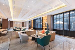 a lobby with couches and tables and windows at Atour Hotel Ningbo Fenghua Huizheng Street in Ningbo