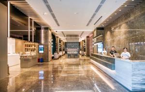 Atour Hotel Guangzhou Huadu Financial Center في هوادو: لوبي فندق فيه ناس جالسين في كونتر
