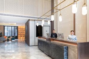 two people sitting at a counter in a lobby at Atour Hotel Ningbo Fenghua Huizheng Street in Ningbo