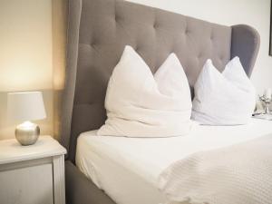 a bed with white pillows on top of it at Stylische Wohnung in ruhiger Lage, sehr messenah in Laatzen