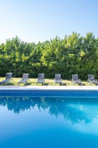 eine Gruppe von Stühlen neben einem Pool in der Unterkunft Masia Ventanell Luxury villa near Barcelona in Llacuna