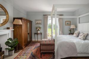 1 dormitorio con cama blanca y espejo en Henge Estate - Restored Manor House, up to 11 en-suite bedrooms, en Shrewton