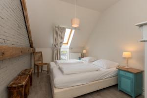 a bedroom with a bed and a chair and a window at Welcome in - Lepelstraat 14, Vrouwenpolder- Knotwilg in Vrouwenpolder