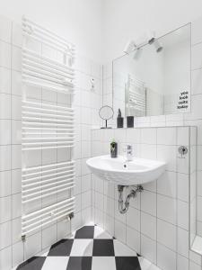 ein weißes Badezimmer mit einem Waschbecken und einem Spiegel in der Unterkunft limehome Berlin Malmöer Straße in Berlin