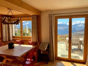 uma sala de jantar com uma mesa e uma grande janela em K2 Chalet em Crans-Montana