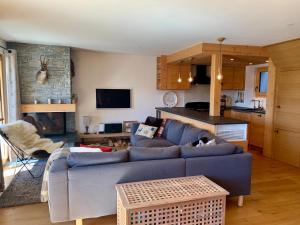 a living room with a blue couch and a kitchen at K2 Chalet in Crans-Montana