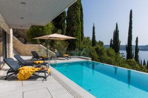 una piscina con sedie, tavolo e ombrellone di Luxury Villa Helios 5* a Dubrovnik