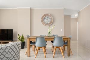 a dining room table with chairs and a clock on the wall at Island Club Luxury Apartments in Cape Town +67 photos