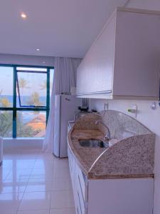 Marulhos Resort Flat Vista Mar في بورتو دي غالينهاس: مطبخ مع حوض ونافذة كبيرة