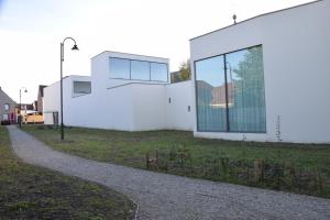 een wit gebouw met glazen ramen aan de zijkant bij CaCeLe Raveelzicht in Zulte