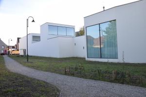 a white building with glass windows on the side of it at CaCeLe Raveelzicht in Zulte