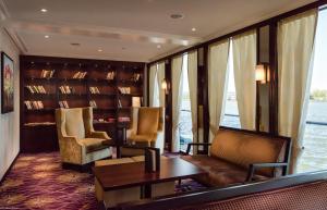 KD Hotelship Düsseldorf Comfort Plus في دوسلدورف: غرفة مع مكتبة مع طاولة وكراسي