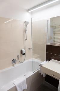 a bathroom with a shower and a tub and a sink at Neufeldersee Hotel & Restaurant in Neufeld an der Leitha