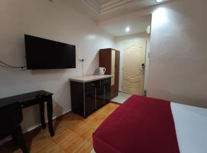 Habitación con cama, escritorio y TV de pantalla plana. en DARUL SALAM INN HOTEL, en Kertih