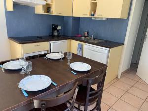 a kitchen with a table with plates and wine glasses at T2 Les jardins Gruissan in Gruissan