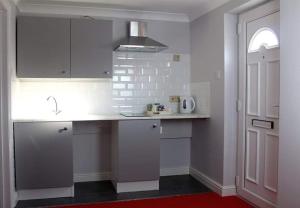 cocina con armarios blancos y alfombra roja en The Sportsman Chalets, en Kent