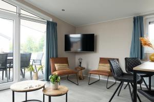 a living room with chairs and a tv on the wall at Chalet bis sechs Personen ohne Hund - a61179 in Norden