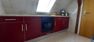 a kitchen with red cabinets and a black oven at Ferienwohnung Vor den Toren Lübecks in Herrnburg