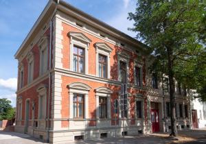 Un edificio de ladrillo rojo con un árbol delante. en Liebknecht 13, en Bernburg