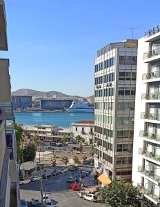 a view of a city with a large building and a harbor at ΜΕ ΘΕΑ ΤΟ ΛΙΜΑΝΙ in Piraeus
