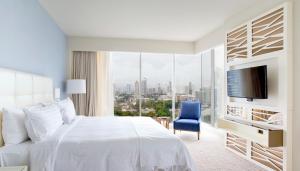 a bedroom with a white bed and a large window at Global Hotel Panama in Panama City