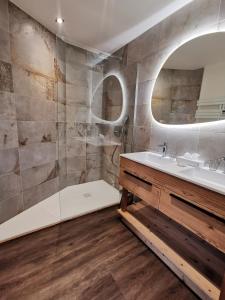 ein Badezimmer mit einem Waschbecken, einer Badewanne und einem Spiegel in der Unterkunft Chalet Jardin d'Angèle Chambres d'hôtes in Courchevel