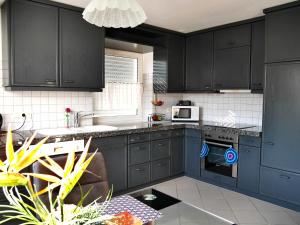 een keuken met donkerblauwe kasten en een magnetron bij Ferienwohnung Lenneblick in Plettenberg